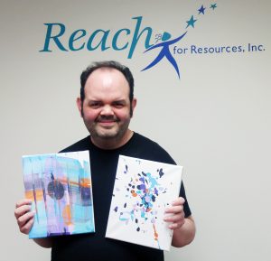 Man holding two oil paintings