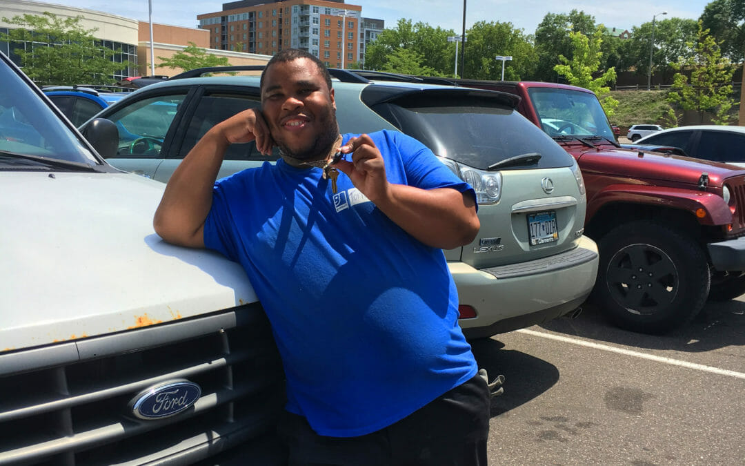 Young man leans on white Ford vehicle hood and danging keys