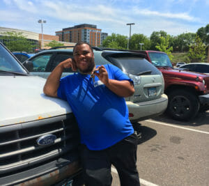 Young man leans on white Ford vehicle hood and danging keys
