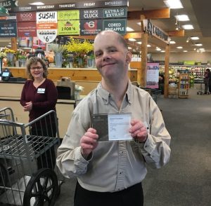 Male employee holding certificate at grocery store