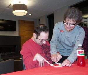woman helping man decorate cookie